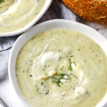 zucchini soup garnished with dill with a loaf of bread