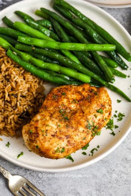 air fryer chicken breast with parsley next to rice and green beans on a plate