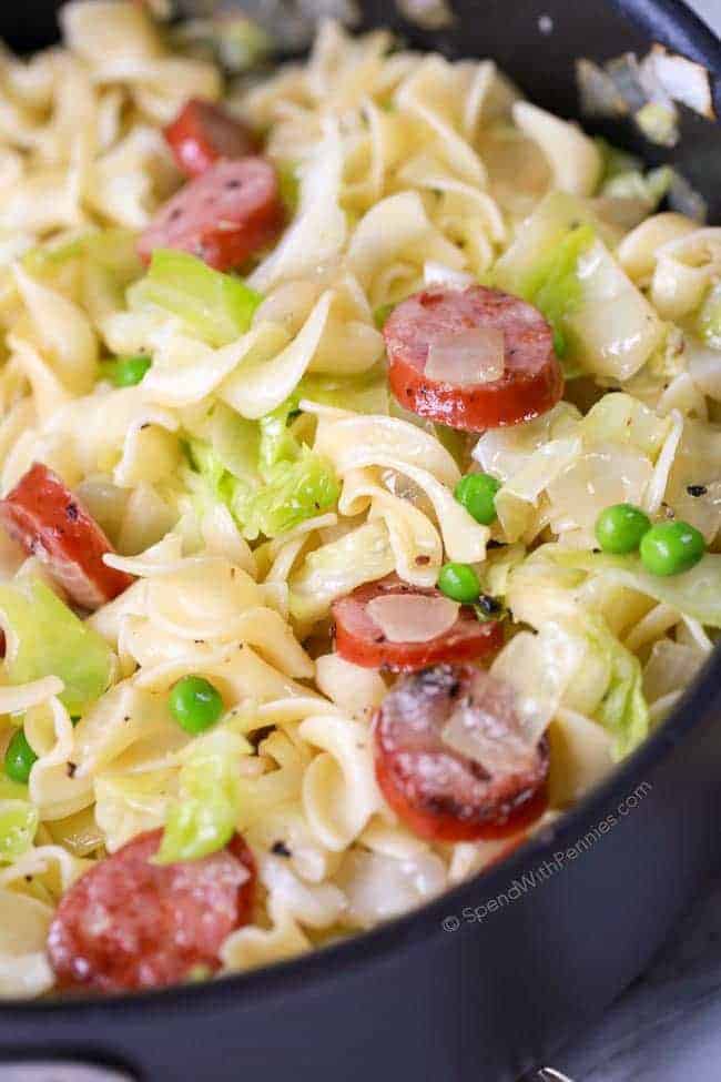 Cabbage and Noodles in a large pan with onions, peas and sausage