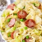 Cabbage and Noodles in a bowl with peas and sausage topped with pepper