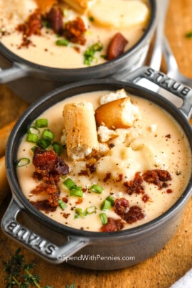 a bowl of cheesy potato soup garnished with green onion and bacon