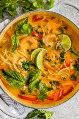 Prepared coconut curry soup topped with basil and lime wedges