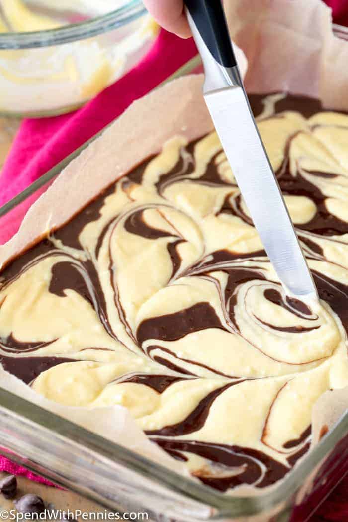 Raw Cream cheese brownies being swirled with a knife