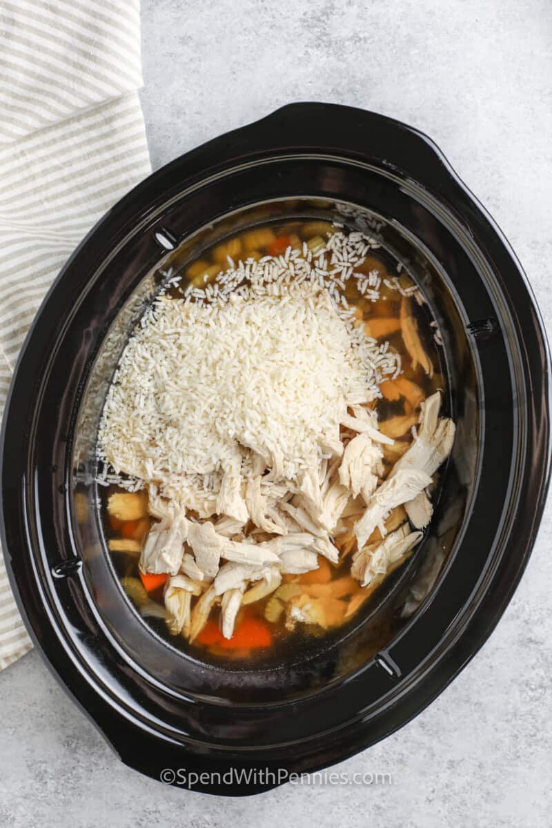 adding rice and chicken to pot to make Crockpot Chicken and Rice Soup