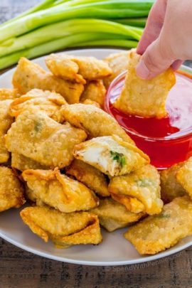 crab rangoon on plate being dipped in sauce