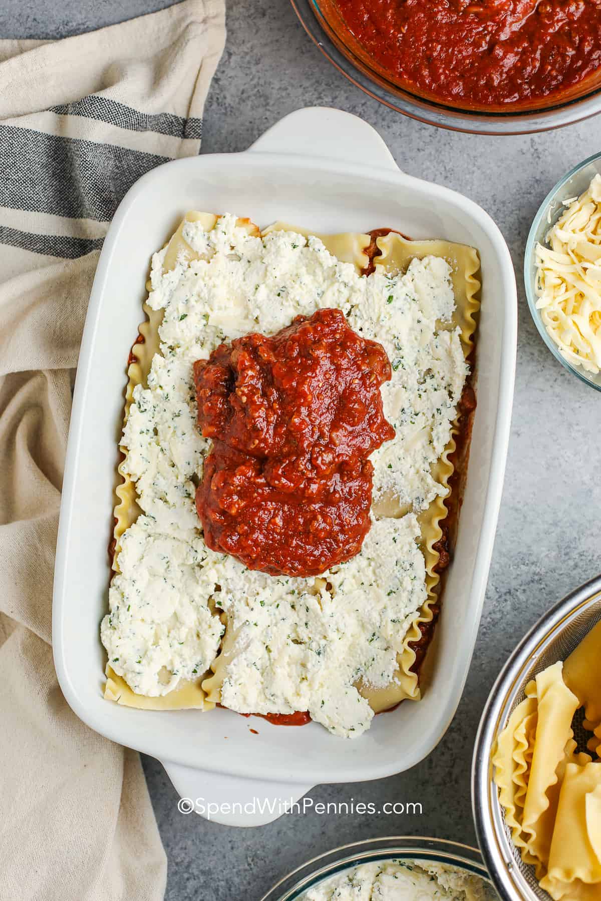 meat sauce on lasagna noodles with ricotta cheese in a baking dish