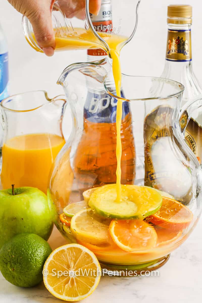 adding orange juice to citrus fruit to make Easy Red Sangria