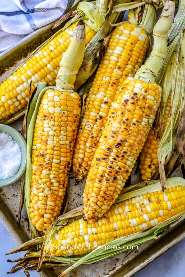 Grilled corn shown on a baking tray with salt