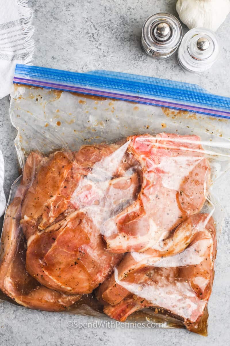 adding chicken to dressing to marinade for Grilled Pork Chops