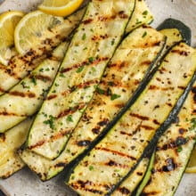 grilled zucchini with lemon wedges on a serving plate