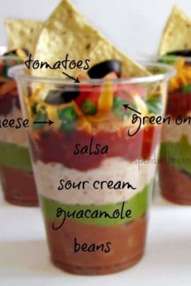 individual seven layer dip ingredients in cups with a tortilla chip