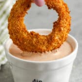 dipping and onion ring into Onion Ring Sauce