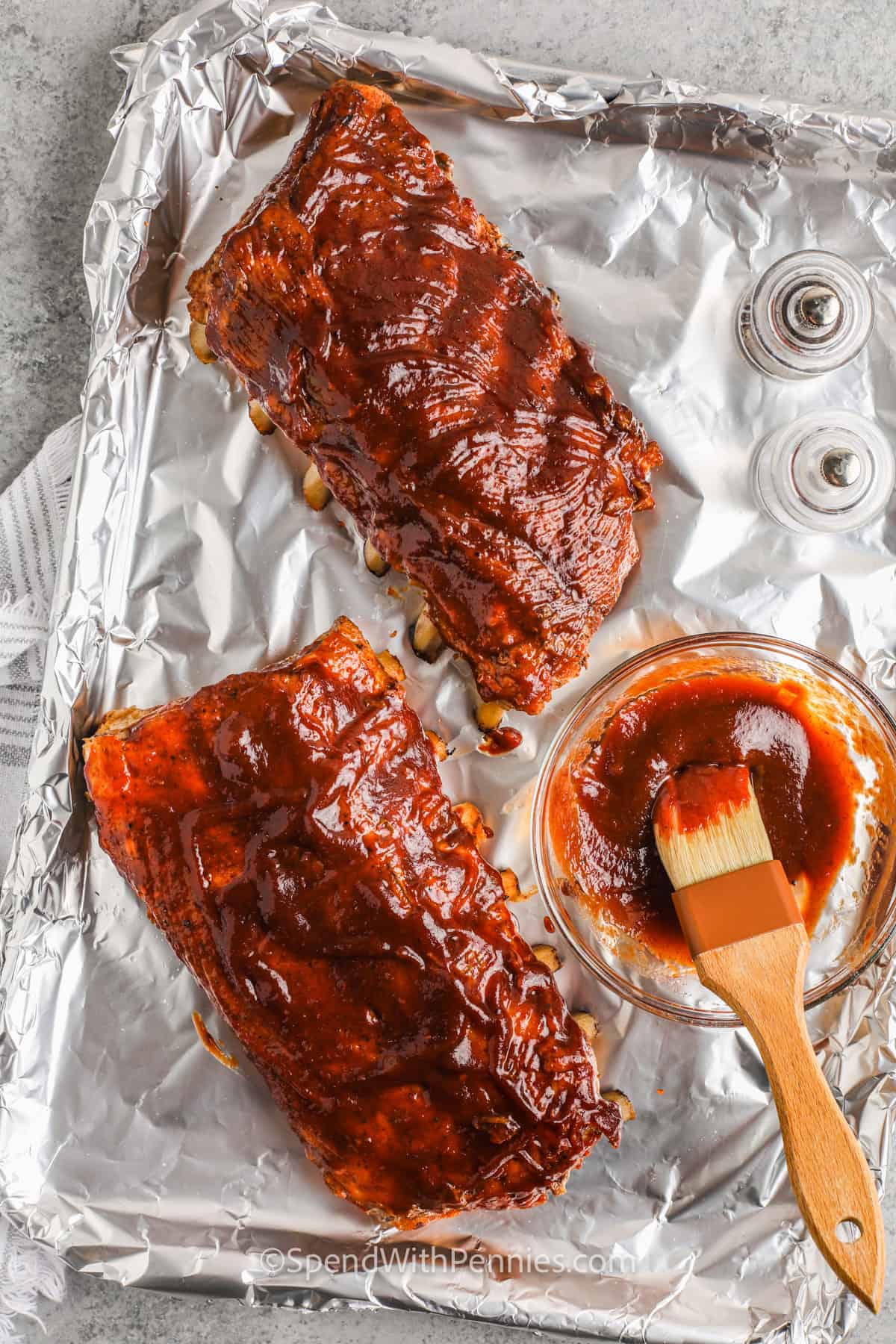 adding sauce to ribs to make Oven Baked Ribs