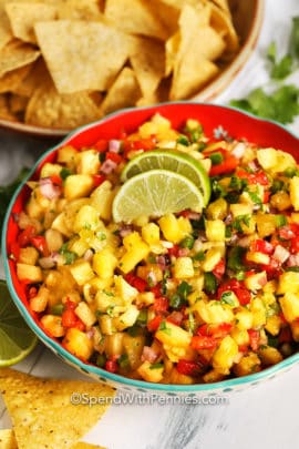 Pineapple salsa topped with lime wedges and cilantro