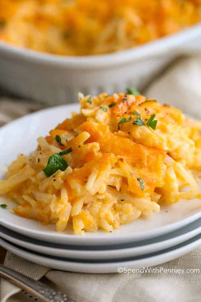 Cheesy hashbrown casserole on a stack of white plates.