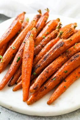 Oven roasted carrots on a marble board garnish with parsley
