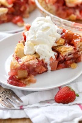 Strawberry Rhubarb Pie on a white plate with vanilla ice cream on top