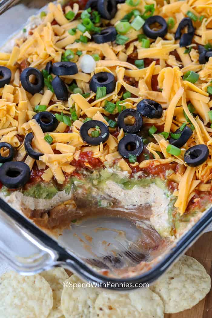 7 Layer Dip in a casserole dish with a scoop taken out