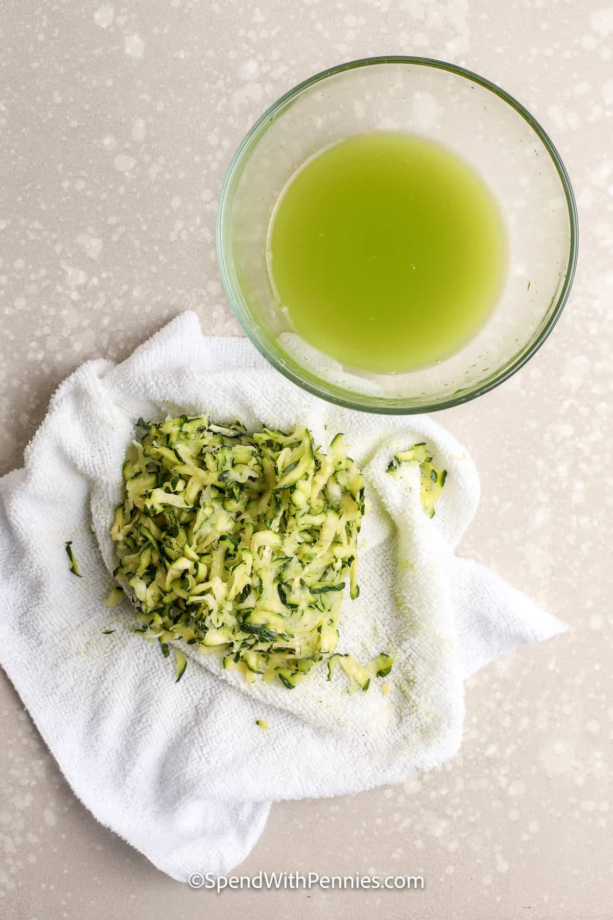 shredded zucchini on a cloth with a bowl of green liquid next to it