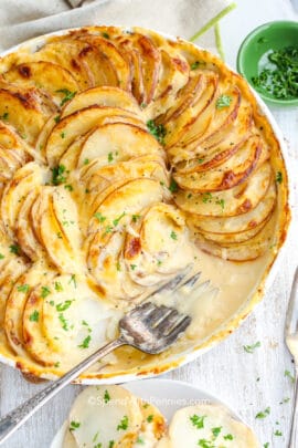 potatoes au gratin in a baking dish with a fork