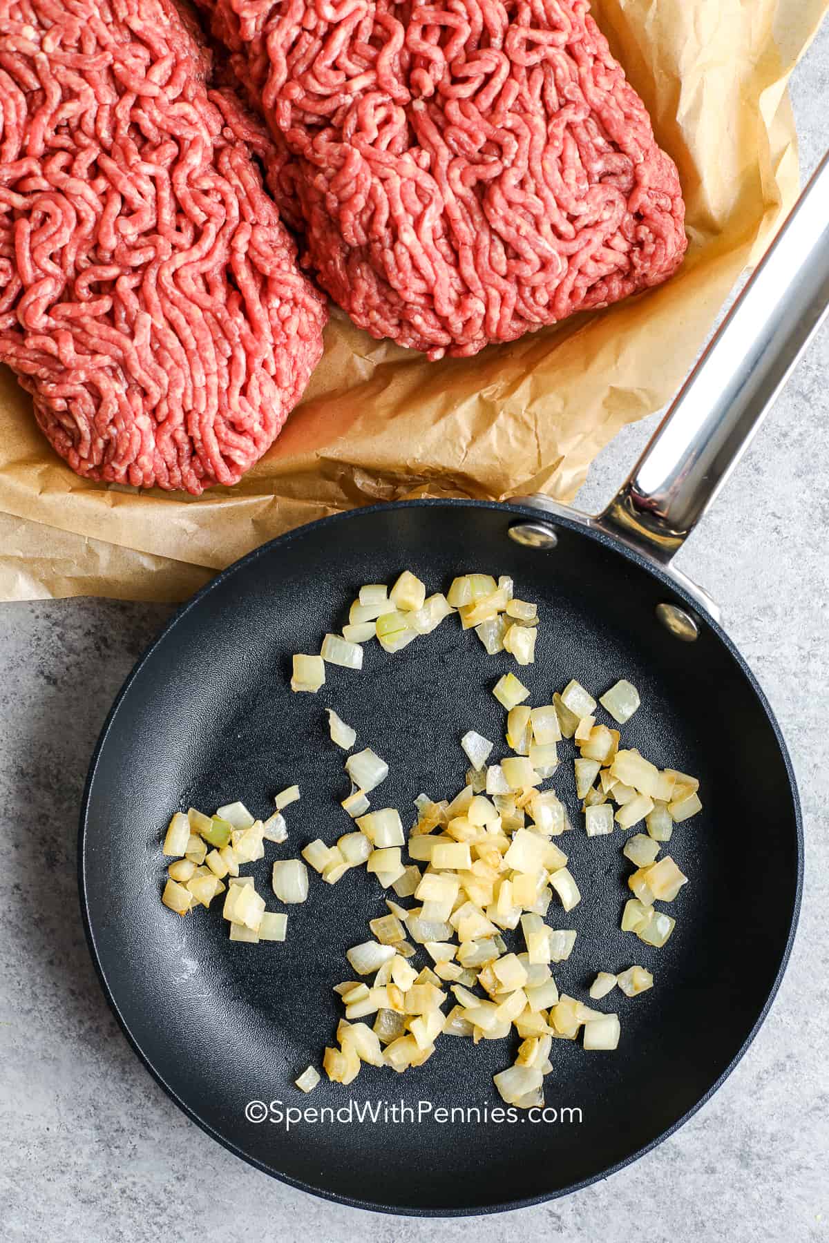 cooked onions in a small skillet next to ground beef for meatloaf
