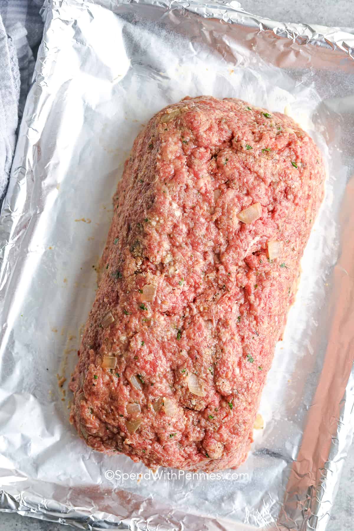 an uncooked formed meatloaf on a foil lined pan